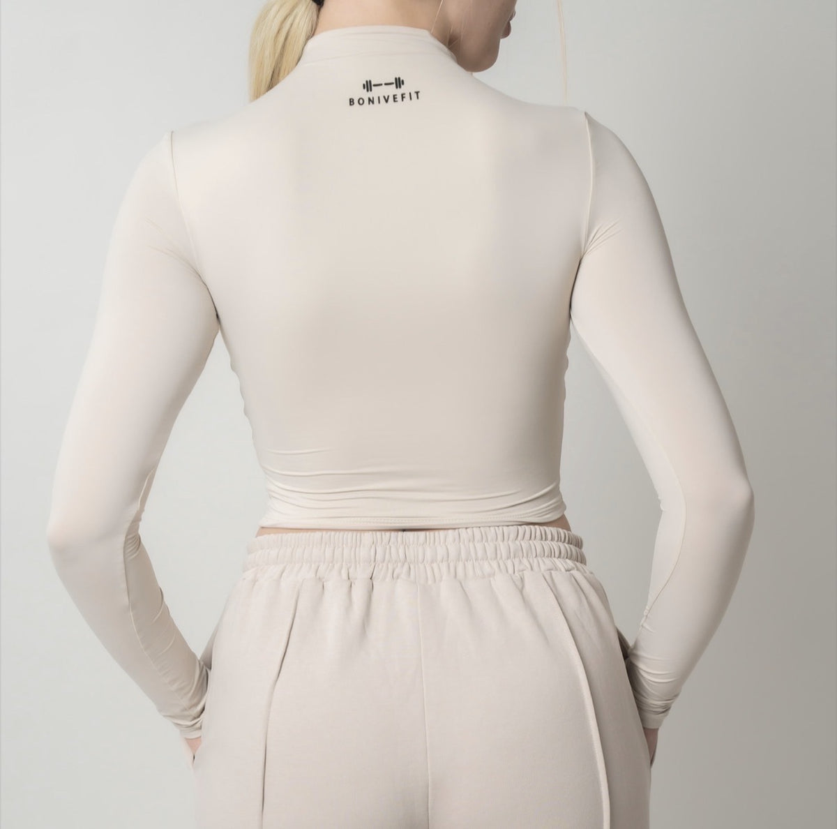 Beige DURA TOP, long-sleeve mock-neck crop top, back view, logo at the back of the neck