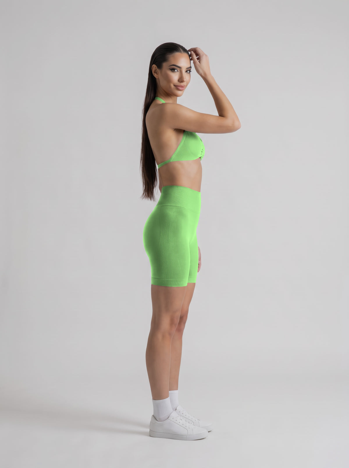 MIAMI VIBES SET verde neón, top halter y short de tiro alto, de perfil, una mano en el pelo